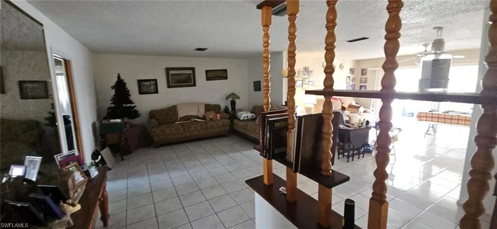 Living room with light tile patterned floors, a textured ceiling, and lofted ceiling