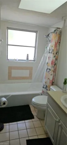 Full bathroom with vanity, toilet, shower / bathtub combination with curtain, and a wealth of natural light