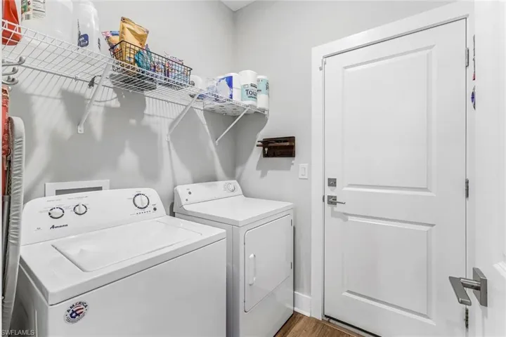 Washroom with laundry area, washing machine and dryer, and wood finished floors