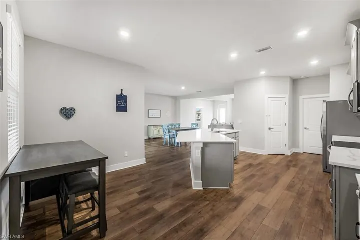 Kitchen with a kitchen island with sink, recessed lighting, baseboards, visible vents, and dark wood-style floors
