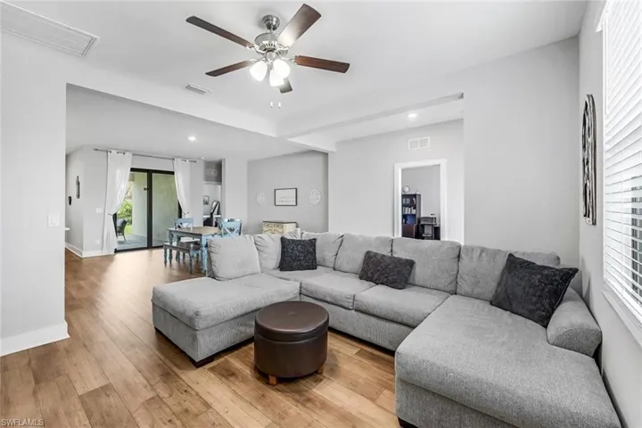 Living room with visible vents, ceiling fan, and wood finished floors
