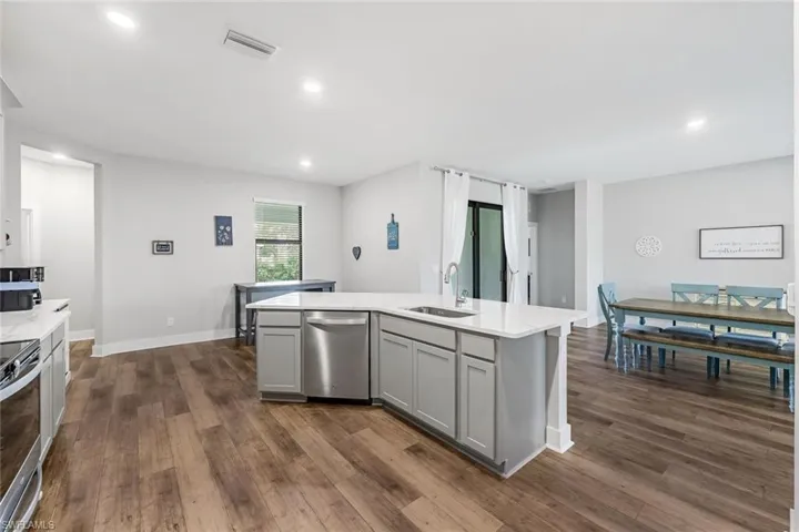 Kitchen with gray cabinets, visible vents, a sink, stainless steel appliances, and an island with sink