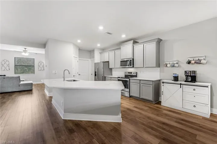 Kitchen with gray cabinets, a sink, light countertops, open floor plan, and stainless steel appliances