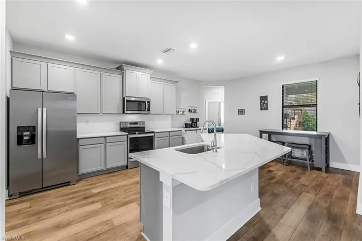 Kitchen featuring recessed lighting, a sink, light wood-style flooring, gray cabinetry, and stainless steel appliances