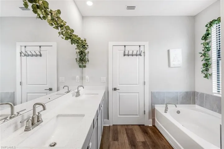 Full bathroom with a sink, wood finished floors, and a wealth of natural light