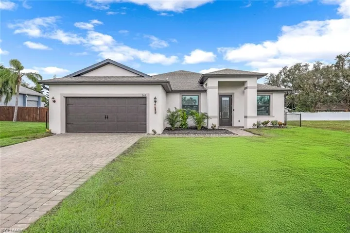 Prairie-style home featuring decorative driveway, a garage, a front yard, and stucco siding