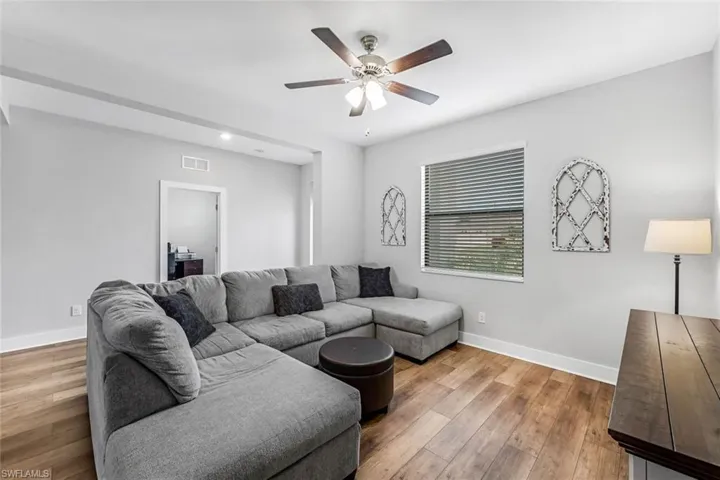 Living area featuring visible vents, baseboards, ceiling fan, and hardwood / wood-style flooring