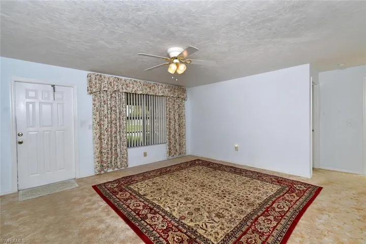 Living room featuring a textured ceiling, ceiling fan, and light colored carpet