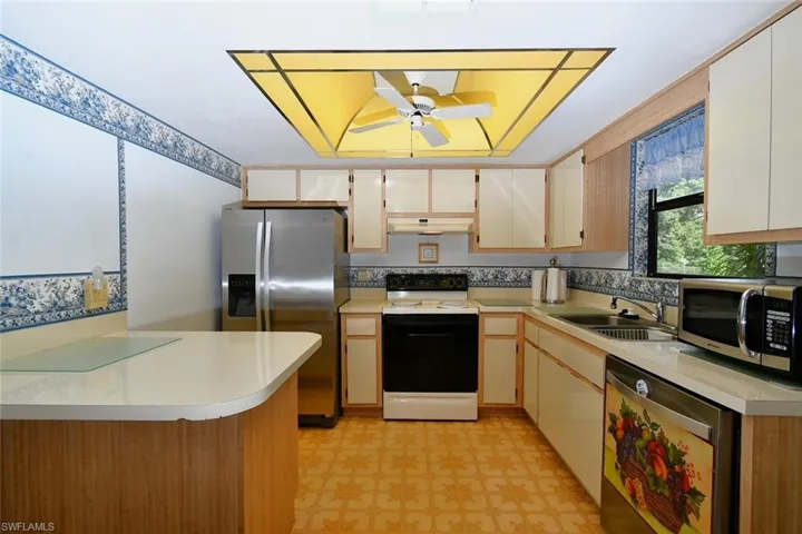 Kitchen featuring stainless steel appliances, sink, kitchen peninsula, light tile patterned floors, and ceiling fan