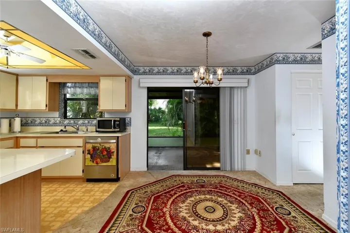 Kitchen with light tile patterned flooring, a textured ceiling, an inviting chandelier, stainless steel appliances, and sink