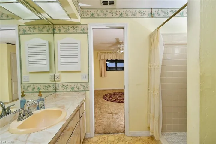 Bathroom featuring tile patterned floors, a shower with curtain, vanity, and ceiling fan