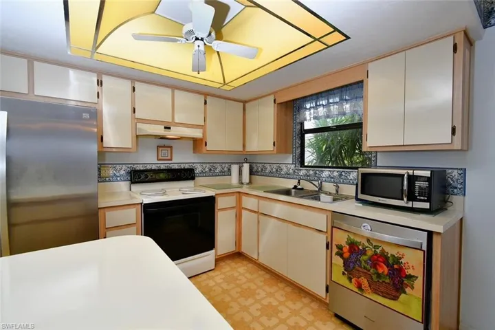 Kitchen featuring light tile patterned flooring, stainless steel appliances, sink, and ceiling fan