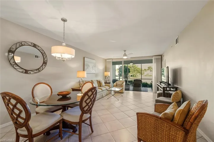 Dining area with a wall of windows, light tile patterned flooring, and a ceiling fan