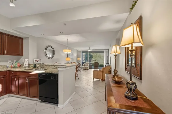 Kitchen with dishwasher, decorative light fixtures, light stone counters, light tile patterned floors, and open floor plan