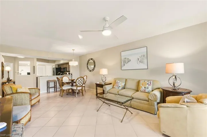 Tiled living room with a ceiling fan and baseboards