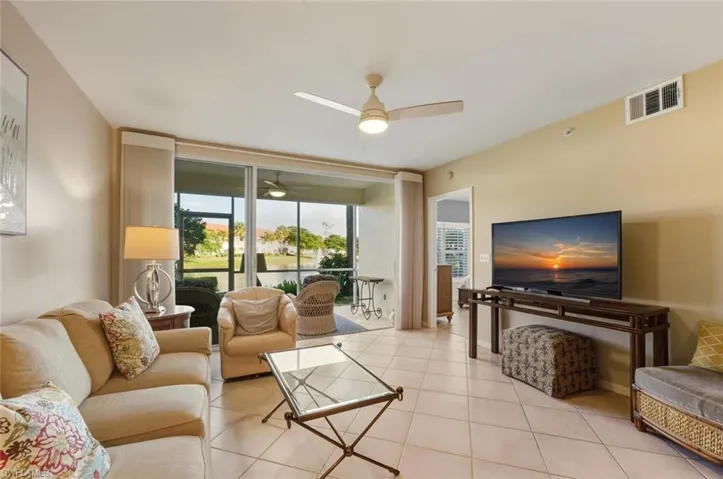 Living area with expansive windows, light tile patterned flooring, and a ceiling fan