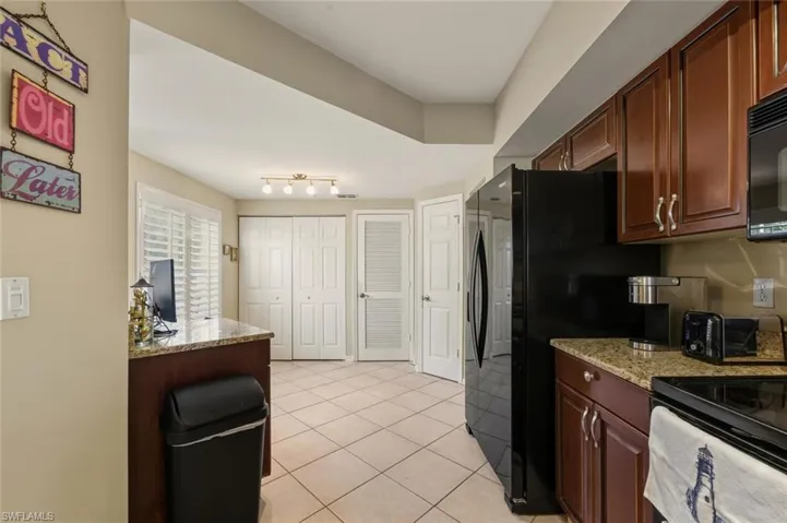 Kitchen with light stone counters, light tile patterned floors, and black appliances