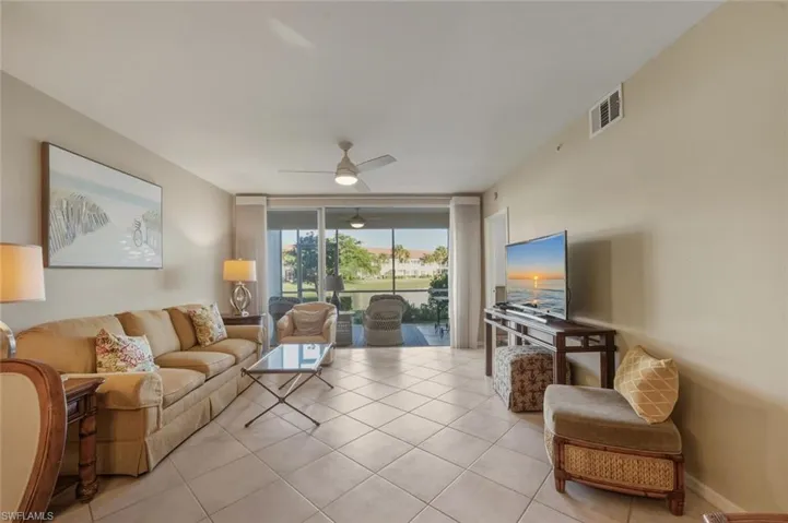 Living room featuring floor to ceiling windows, light tile patterned floors, and a ceiling fan