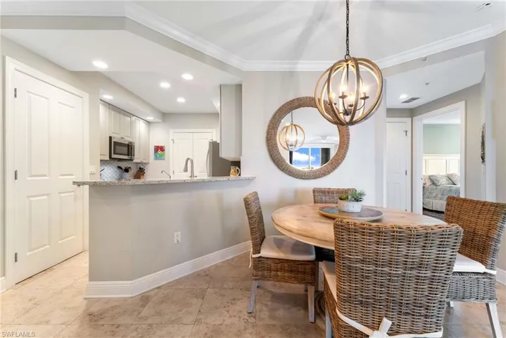 Dining area with sink, crown molding, and a chandelier