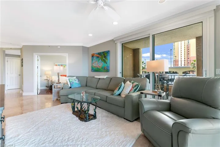 Tiled living room with ceiling fan and crown molding