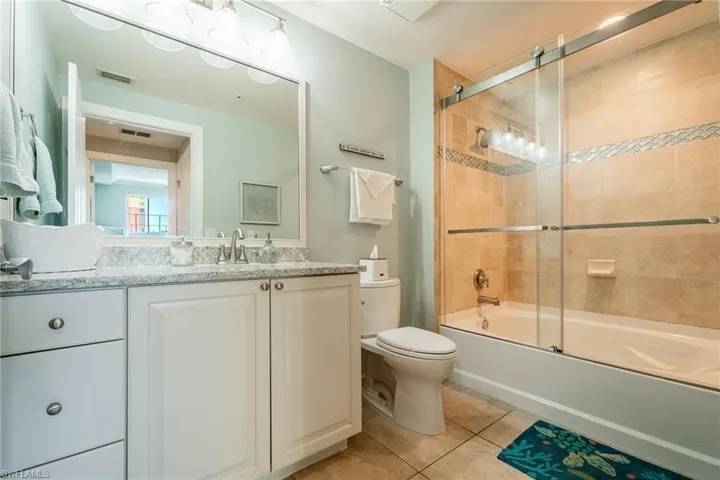 Full bathroom featuring tile patterned flooring, vanity, toilet, and combined bath / shower with glass door