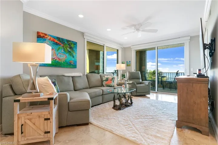 Tiled living room with ceiling fan, crown molding, and a wall of windows