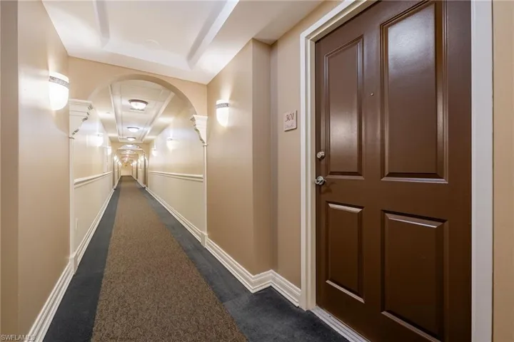 Hall featuring a tray ceiling and dark carpet