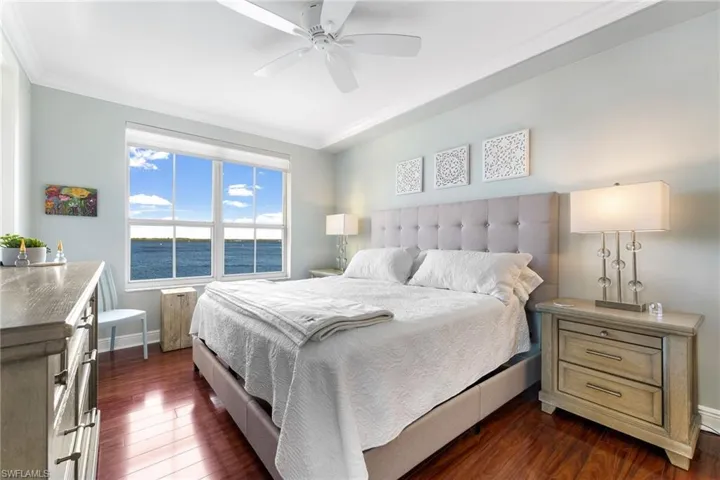 Bedroom featuring ceiling fan, a water view, ornamental molding, and dark wood-type flooring