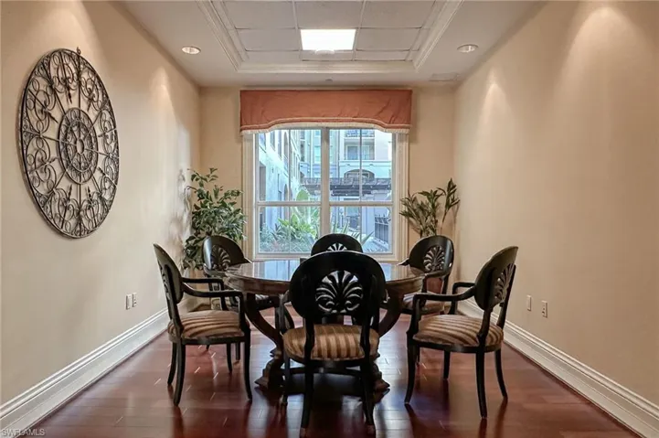 Dining area featuring a raised ceiling, ornamental molding, and dark wood-type flooring