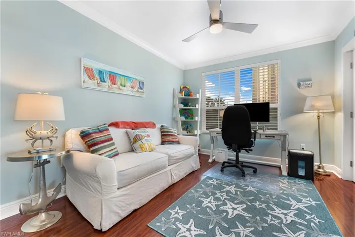 Office area with ceiling fan, dark hardwood / wood-style flooring, and ornamental molding