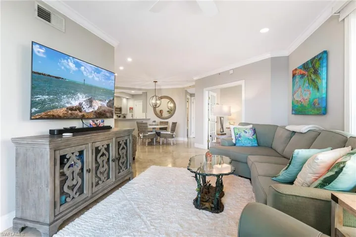 Living room with ceiling fan with notable chandelier and crown molding