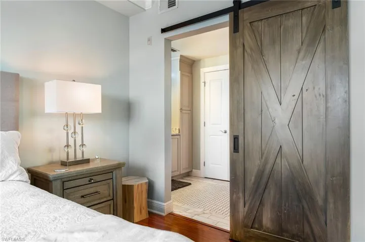 Bedroom with a barn door and dark hardwood / wood-style flooring