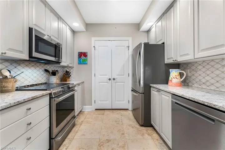 Kitchen with backsplash, stainless steel appliances, and white cabinetry