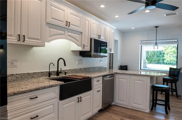 Kitchen featuring visible vents, stainless steel dishwasher, a sink, a peninsula, and white cabinetry