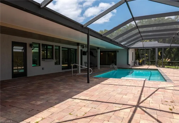 Pool featuring glass enclosure and a patio
