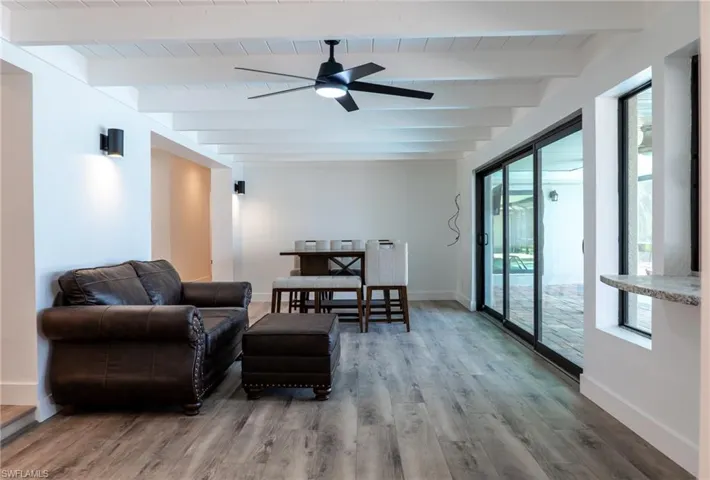 Living room featuring beamed ceiling, wood finished floors, and baseboards