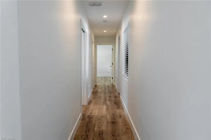 Hallway featuring recessed lighting, light wood-style floors, visible vents, and baseboards