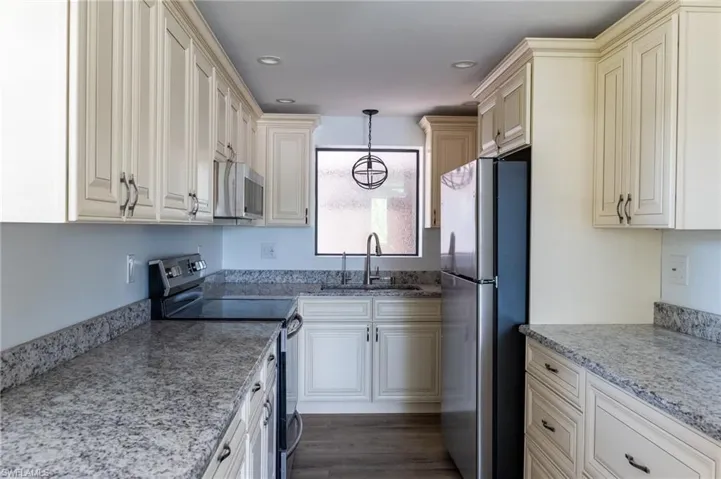 Kitchen featuring recessed lighting, stainless steel appliances, a sink, light stone countertops, and pendant lighting