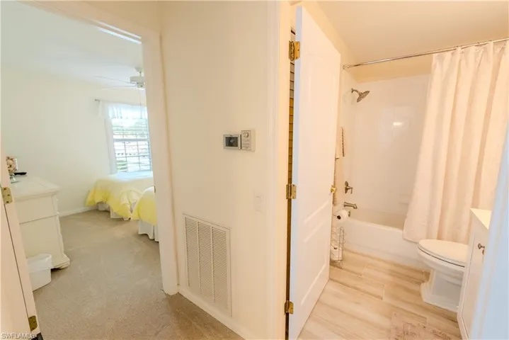 Full bathroom featuring hardwood / wood-style floors, shower / bath combination with curtain, toilet, vanity, and ceiling fan