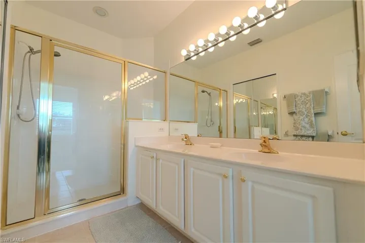 Bathroom featuring dual vanity, an enclosed shower, and tile patterned flooring