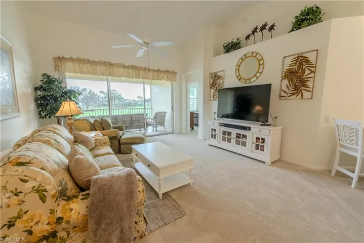 Living room with light carpet, high vaulted ceiling, and ceiling fan
