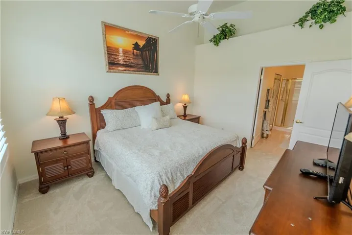 Carpeted bedroom featuring connected bathroom and ceiling fan