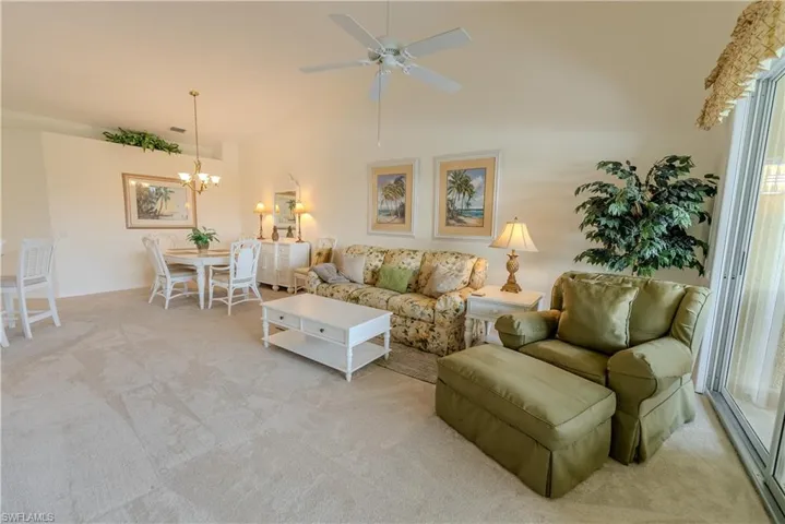 Carpeted living room with ceiling fan with notable chandelier
