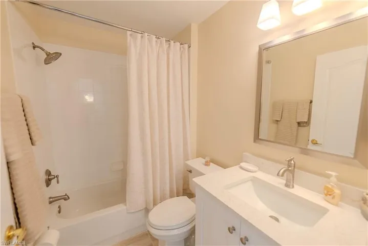 Full bathroom with vanity, shower / bath combo with shower curtain, and toilet