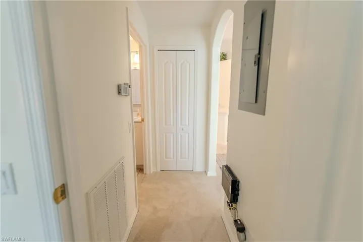 Hallway with electric panel and light colored carpet