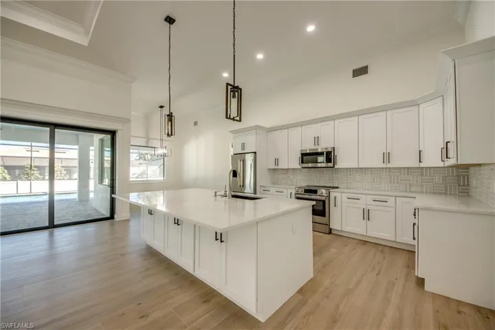 Kitchen featuring a center island with sink, appliances with stainless steel finishes, sink, and white cabinetry