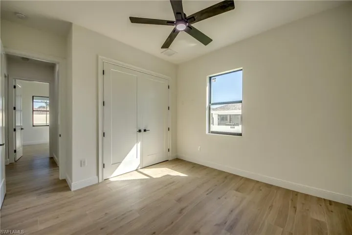 Unfurnished bedroom featuring a closet, light hardwood / wood-style flooring, multiple windows, and ceiling fan