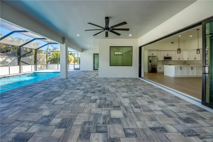 View of pool featuring a patio, glass enclosure, and ceiling fan