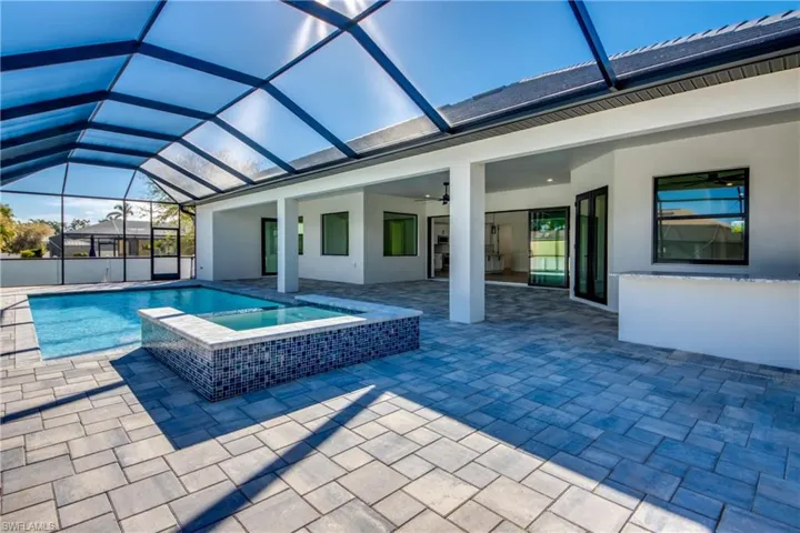 View of swimming pool featuring an in ground hot tub, glass enclosure, a patio area, and ceiling fan