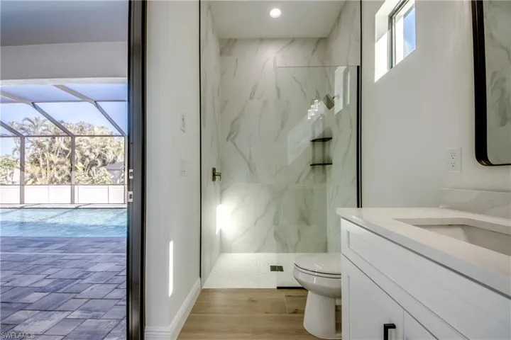 Bathroom with a tile shower, hardwood / wood-style floors, vanity, and toilet